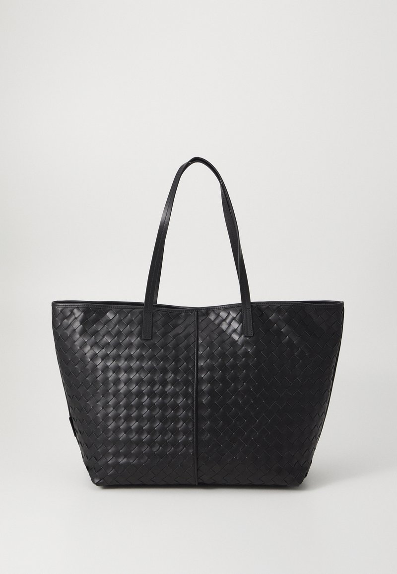 Black woven tote bag with two long handles, featuring a rectangular shape and textured surface design. No visible closures or embellishments.