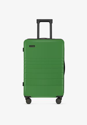 Hartschalenkoffer in grün mit horizontalen Rillen, schwarzem Griff und vier Mobilitätsrädern. Reißverschlussverschluss an der Oberseite. Leichtes Design.