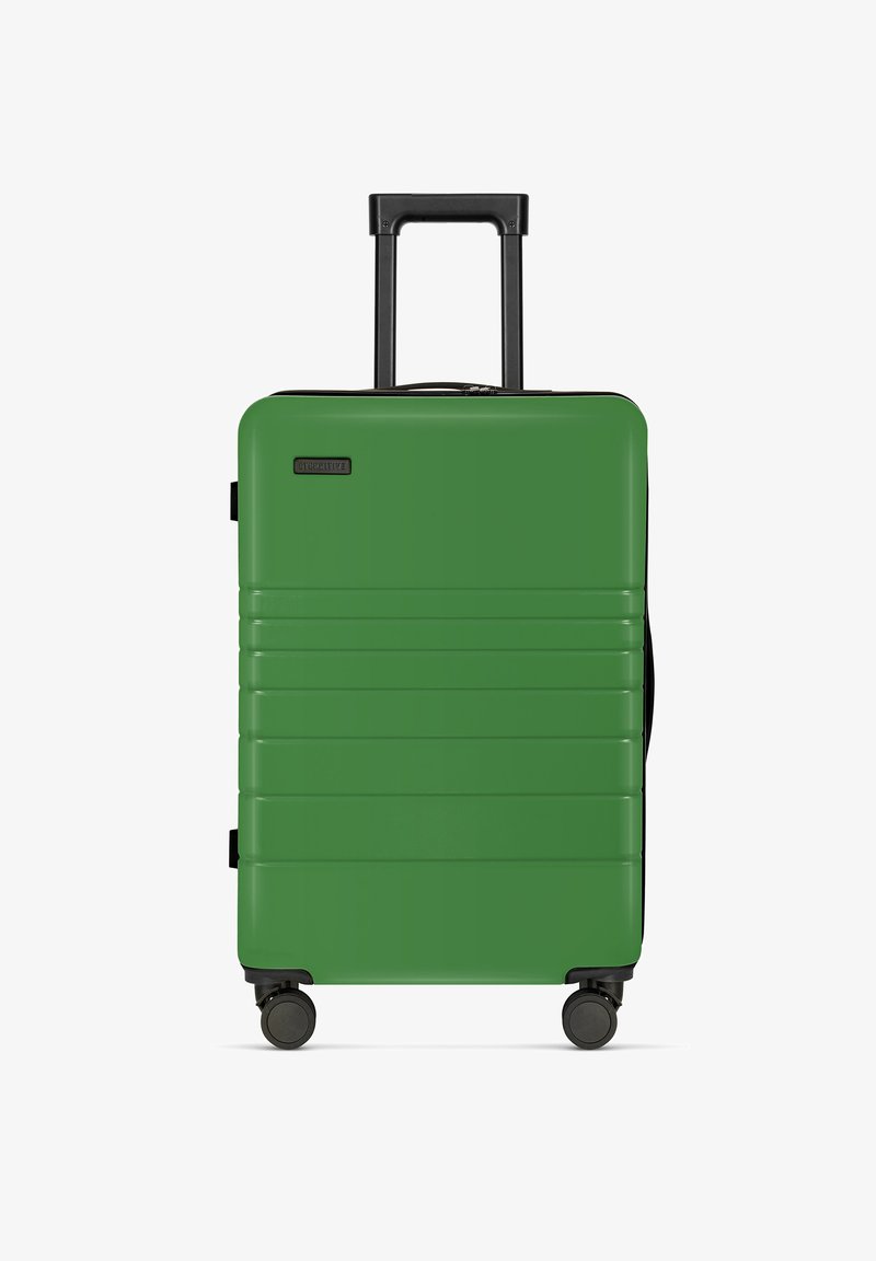 Hartschalenkoffer in grün mit horizontalen Rillen, schwarzem Griff und vier Mobilitätsrädern. Reißverschlussverschluss an der Oberseite. Leichtes Design.