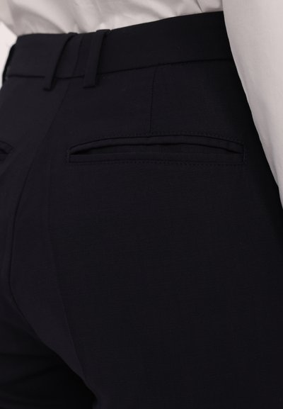 Námořnické modré kalhoty na míru s hladkým povrchem, obsahující dvě zadní kapsy a moderní design pasu.