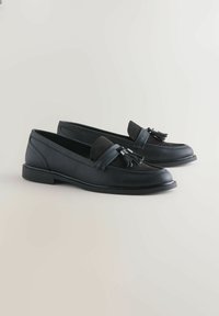 Sorte loafers lavet af læder og ruskind, med en flad sål, kvastdetaljer og en glat finish med syede detaljer.