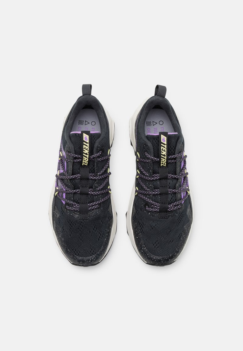 Schwarze Sportschuhe aus strukturiertem Material, mit lila Akzenten und gemusterten Schnürsenkeln. Sie verfügen über eine dicke weiße Sohle und eine Zuglasche an der Rückseite.