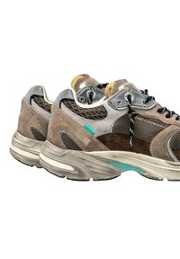 Sneaker in suede e mesh marrone con texture presentano dettagli argentati, lacci neri e un particolare turchese sulla suola intermedia, dalla forma arrotondata.