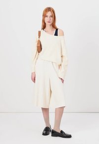 Cream oversized sweater, wide cream shorts, black shoes, and nude socks. Simple design, relaxed fit, soft texture, no prominent patterns.