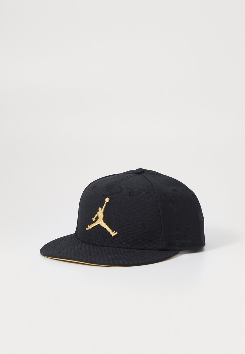 Cappello nero a visiera piatta con un logo ricamato in oro di un giocatore di basket sul davanti e un bordo dorato sul lato inferiore della visiera.