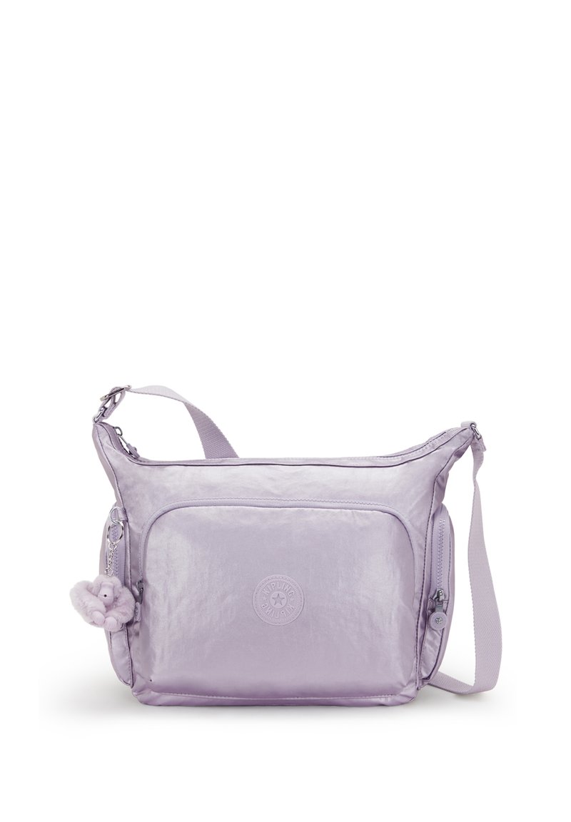 Jasnofioletowa torebka typu crossbody z przednią kieszenią na zamek, bocznym zamkiem, regulowanym paskiem oraz małym pluszowym breloczkiem w kształcie małpki przymocowanym do niej.