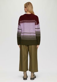 Gebreide trui met een kleurverloop van bordeauxrood, lavendel en olijf, met gestructureerde strepen. Gecombineerd met olijfgroene wijde broek en enkellaarsjes.