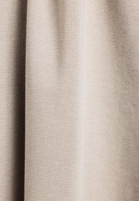 Lichtbeige textiel met een subtiel geweven patroon, dat een soepele val en een consistente oppervlakkwaliteit toont.