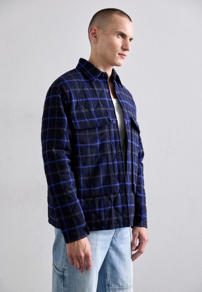 Navy blue flannel shirt with a checkered pattern in blue and gray, featuring a collar, front buttons, and two chest pockets.