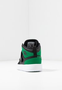 Baskets montantes en cuir noir et matériau synthétique vert, avec une semelle en caoutchouc blanc et un logo distinct sur le côté.