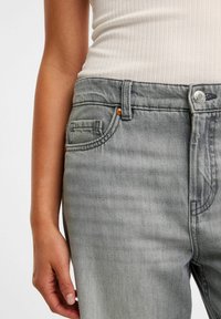 Grijze denim jeans met een licht vervaagde textuur, voorzien van een knoop- en ritssluiting, voorzakken en een laag uitgesneden tailleontwerp.