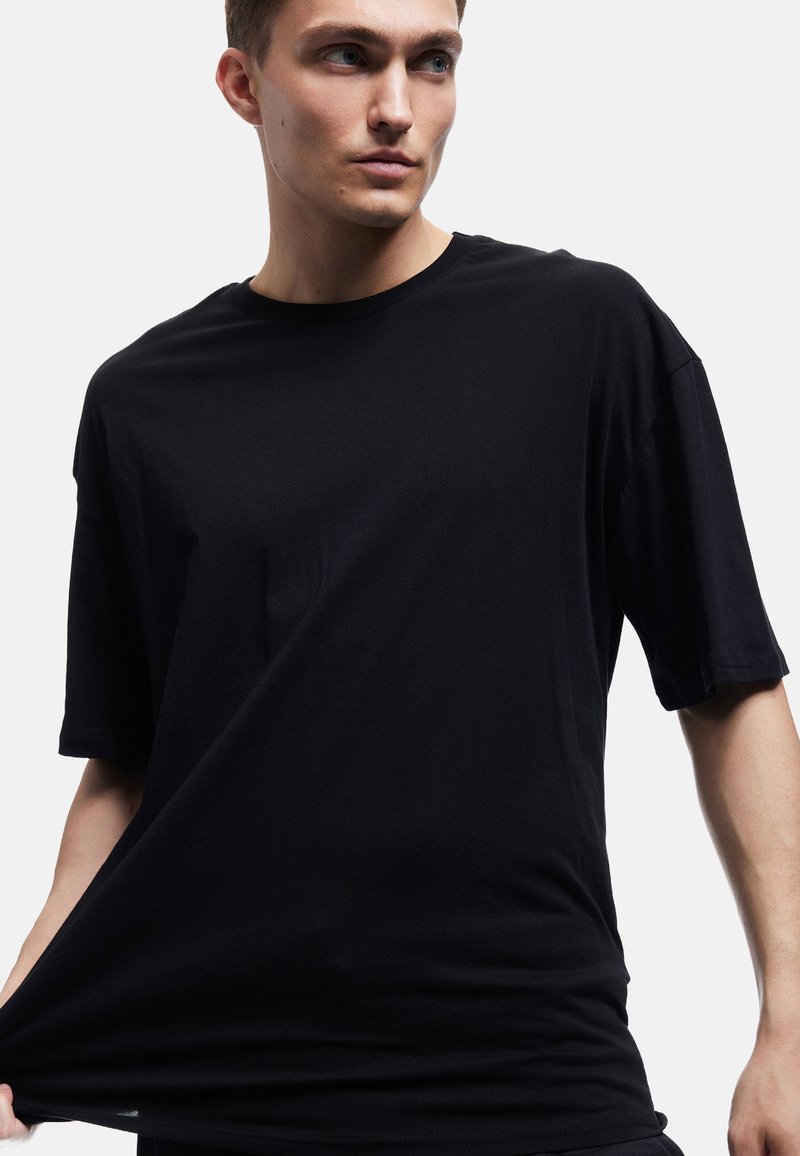 Sort kortærmet t-shirt lavet af blødt, glat stof. Har en rund halsudskæring og en oversized pasform med en let drapering.