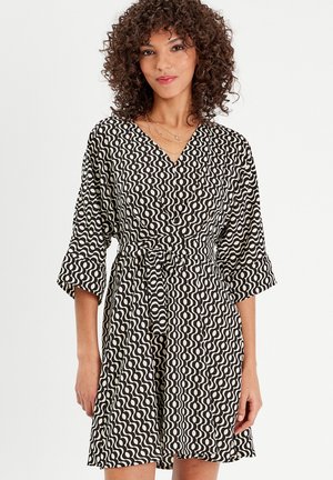 Schwarz-weißer, gemusterter Kleid mit V-Ausschnitt, ausgestellt Ärmel und gebundenem Taillenbereich. Es hat einen wellenförmigen Druck mit einer glatten Textur.
