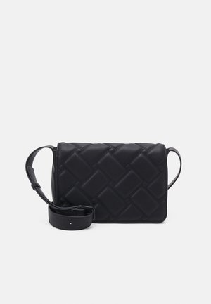 Sac bandoulière noir matelassé avec bandoulière réglable posé à plat sur un fond clair uni.