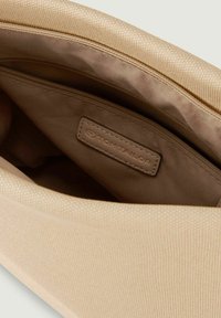 Beżowa tekstylna saszetka z gładkim wnętrzem, z kieszonką na zamek i widoczną metką marki. Teksturowana zewnętrzna powierzchnia.