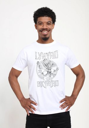 White cotton t-shirt featuring a black graphic print of an eagle and guitar with text "LYNYRD SKYNYRD" and the number "79." Short sleeves, crew neck.