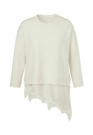 Long-sleeve off-white top with round neck and asymmetrical hem featuring lace trim on the lower right side.