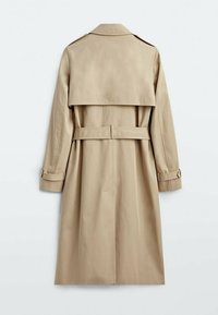 Trench coat beige con vita regolabile, maniche lunghe e design doppiopetto. Presenta una larga aletta posteriore e fascette sui polsini.