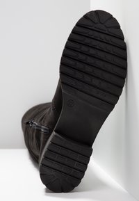 Bottine noire en suède texturé, semelle en caoutchouc avec motif adhérent, et fermeture éclair latérale. Taille indiquée : 37.