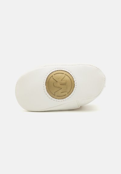 Weißer Lederschuh mit runder Zehenpartie und einem strukturierten goldenen kreisförmigen Logo an der Seite. Genähte Details entlang der Kanten.