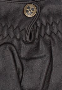 Czarna skórzana tkanina z marszczoną sekcją, ozdobiona brązowym guzikiem w kratkę oraz widocznymi detalami szycia.