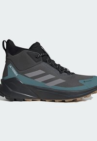 Czarne i szmaragdowe wysokie buty outdoorowe z szarymi akcentami, teksturowana siateczka górna, agresywna podeszwa oraz etykieta GORE-TEX dla odporności na wodę.
