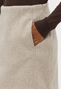 Helehall villaseeliku, millel on sirge lõige, küljetasku, peene tekstuur ja puhas õmblus äärealadel.