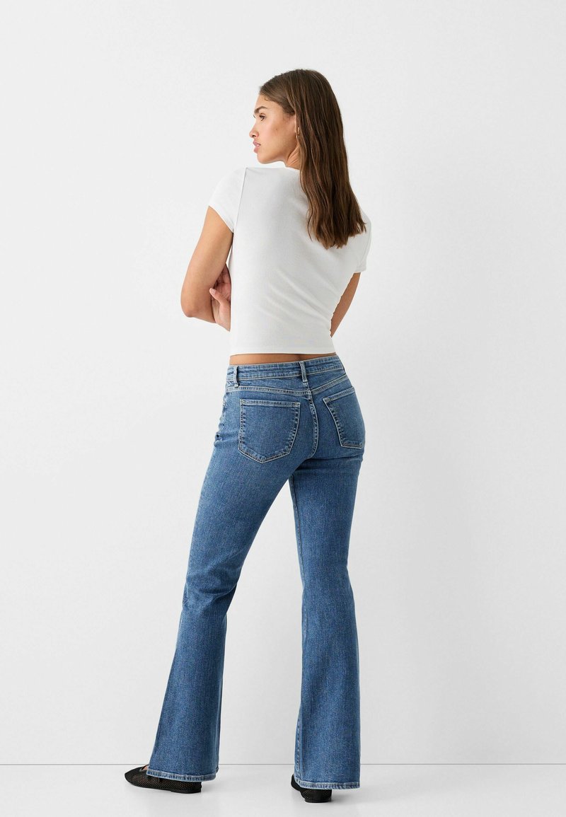Jeans a zampa d'elefante di colore blu con un design classico, caratterizzati da una vita media, due tasche posteriori e una leggera sfumatura nella trama del tessuto.
