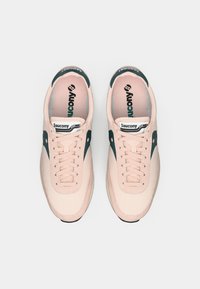 Ténis Saucony em rosa pálido com detalhes em verde escuro, apresentando um material de camurça suave, bico redondo e atacadores padrão.