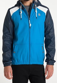 Blå och marinblå vattentät jacka med huva, som har vita axelaccenter, dragkedjefickor och justerbara dragsnören.