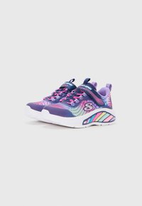 Sneakers per bambini viola e rosa con suole multicolore che si illuminano, lacci rosa e strappi in Velcro su uno sfondo bianco semplice.