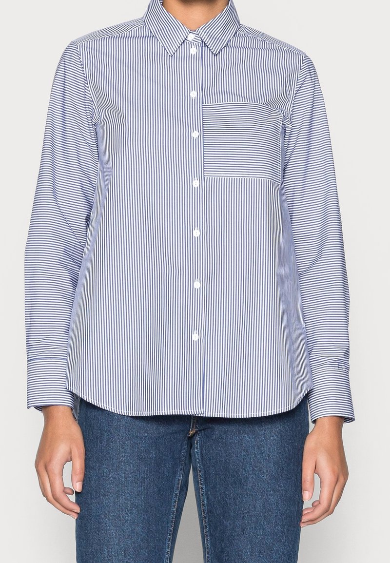 Modrá a bílá pruhovaná košile na knoflíky s límečkem, dlouhými rukávy a kapsou na levé straně hrudi; vyrobená z hladké látky s přizpůsobeným střihem.