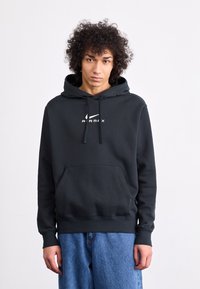 Crna majica s kapuljačom i prednjim džepom, sa vezicom na kapuljači i bijelim "AIRMAX" logotipom. Mekani materijal, regularni kroj, sa rebrastim manžetama i donjim rubom.