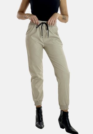 Pantalones jogger beige hechos de una tela suave, que cuentan con una cintura elástica con un cordón negro y puños elásticos en los tobillos.