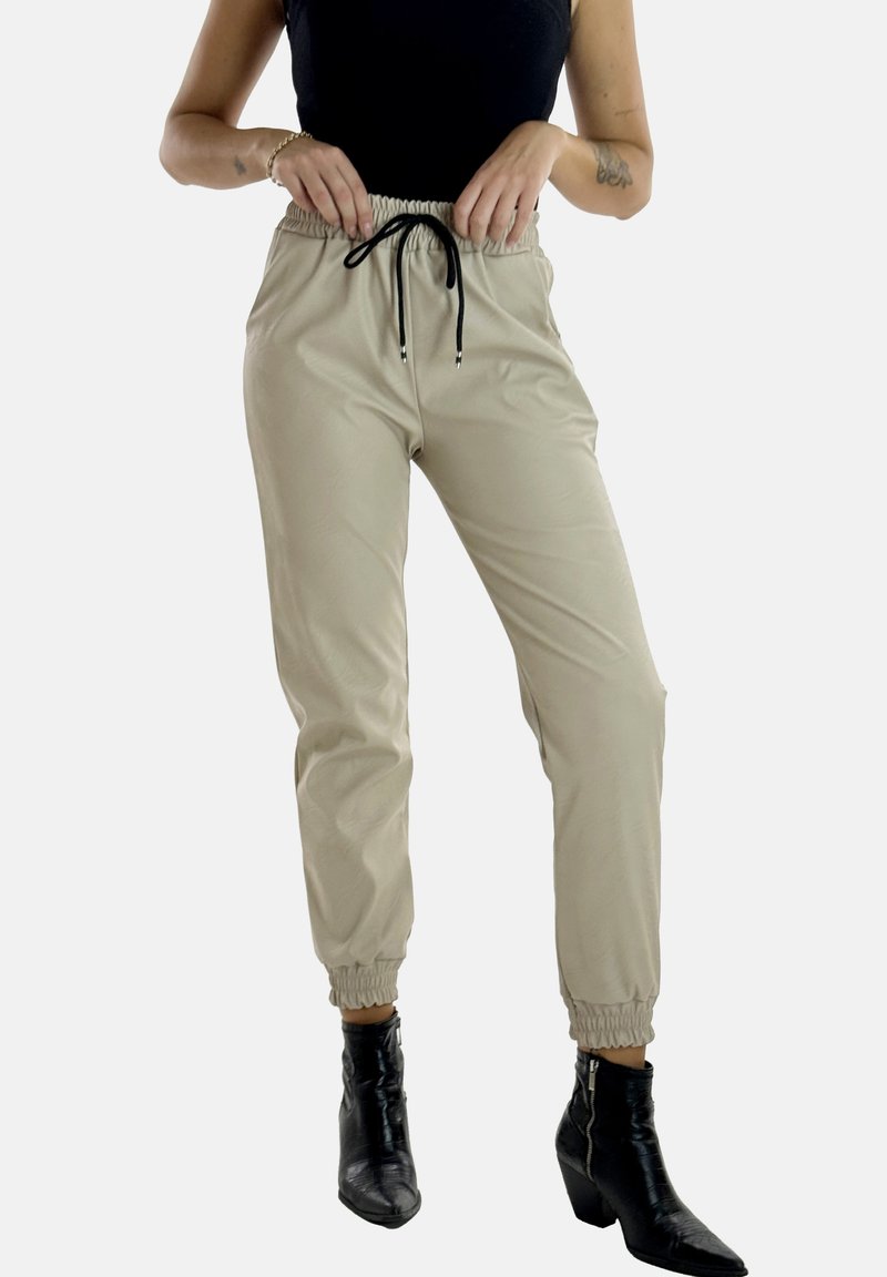 Pantalones jogger beige hechos de una tela suave, que cuentan con una cintura elástica con un cordón negro y puños elásticos en los tobillos.
