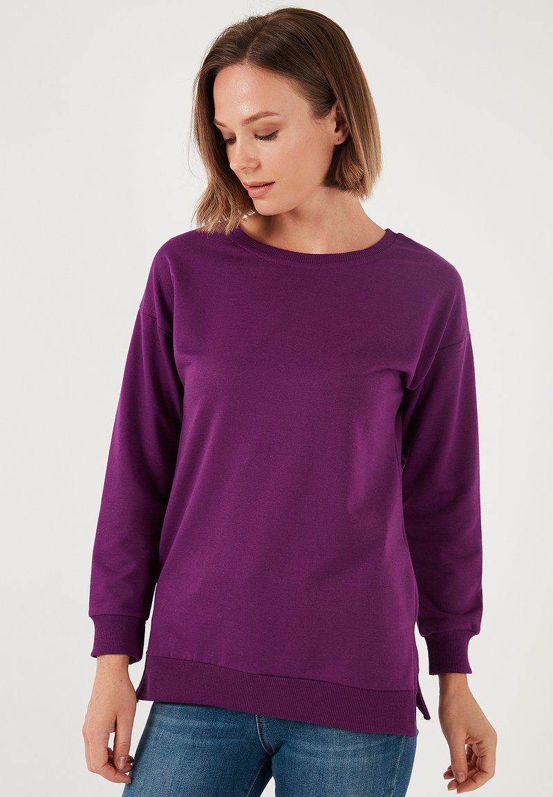 Felpa lunga viola con maniche lunghe, scollo rotondo, polsini a costine e spacchi laterali. Realizzata in tessuto morbido, adatta per un abbigliamento casual.