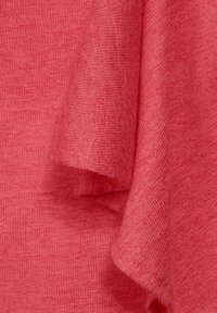 Koralowy dzianinowy materiał o miękkiej fakturze, charakteryzujący się subtelnymi różnicami w odcieniach i wzorach. Materiał jest lekki i pięknie się układa.