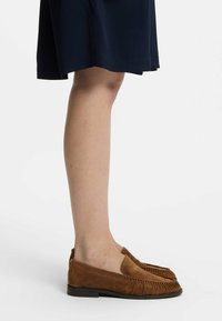 Καφέ σουέτ loafers με στρογγυλή μύτη και gathered λεπτομέρειες στο πάνω μέρος. Η σόλα είναι επίπεδη και ελαφρώς μαλακή για άνεση.