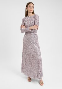 Langärmliges, bodenlanges Kleid aus hellrosa Paillettenstoff. Es hat aufwendige Muster und Texturen, einen runden Ausschnitt und eine taillierte Silhouette.