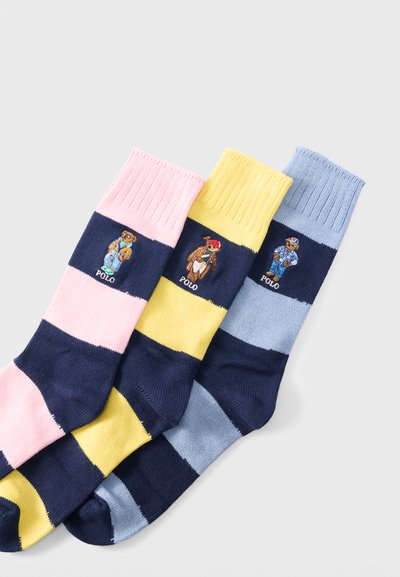 Τρεις ριγέ κάλτσες σε ροζ, κίτρινο και μπλε με ναυτικά μπάντες, που φέρουν κεντημένες αρκουδάκια Polo με διαφορετικές στολές σε κάθε κάλτσα.