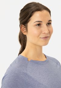 Helles Blau, kurzärmliges Oberteil aus weichem Stoff mit einem runden Halsausschnitt und einem Schlitzdetail sowie einer dezenten Textur im Material.