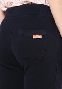 Marina joggers har en bakficka med en orange "Superdry"-etikett, tillverkade av mjukt material med strukturerad ribbad midja.