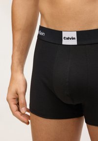 Boxeri din bumbac negri, cu un elastic în talie ce prezintă logo-ul Calvin Klein în alb și negru, detalii cu cusături laterale și un design care se mulează confortabil.