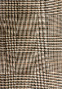 Tissu à carreaux marron, beige et noir avec un motif pied-de-poule dans un motif à grille à carreaux.