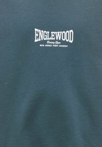 Ciemnozielony bawełniany sweatshirt z białym napisem "ENGLEWOOD Boxing Gym" oraz "NEW JERSEY FIGHT ACADEMY". Miękka faktura.