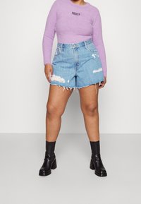 Světle fialový, lehoučký dlouhý rukáv se znakem "RAGGED", v kombinaci se světle modrými džínovými šortkami s opotřebovanými detaily a roztřepeným lemem. Černé kotníkové boty.