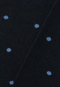 Marineblaues Strickgewebe mit verstreuten hellblauen Punkten, glatte Textur mit weichem Finish und einem dezenten diagonalen Webmuster.