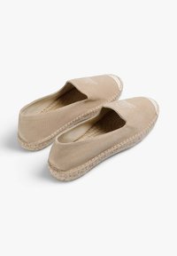 Beige canvas espadrilles met een ronde neus, elastische bovenrand en jute touw zool. Beschikt over een eenvoudig logo op de bovenkant. De textuur is glad.