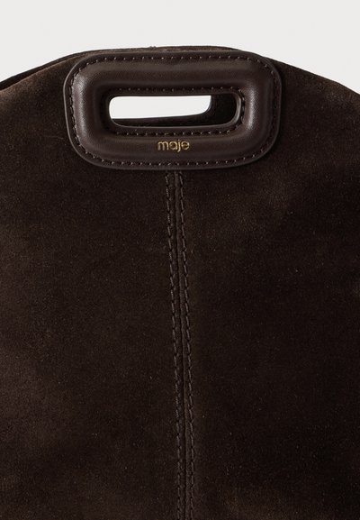 Sac en daim marron foncé avec poignée rectangulaire découpée encadrée de cuir et petit logo doré "moje" sous la poignée.