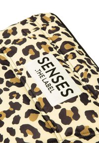 Leopardenmuster gestepptes Gewebe in Beige- und Brauntönen mit schwarzem Rand. Enthält ein weißes Etikett mit der Aufschrift "SENSES THE LABEL" in schwarzer Schrift.